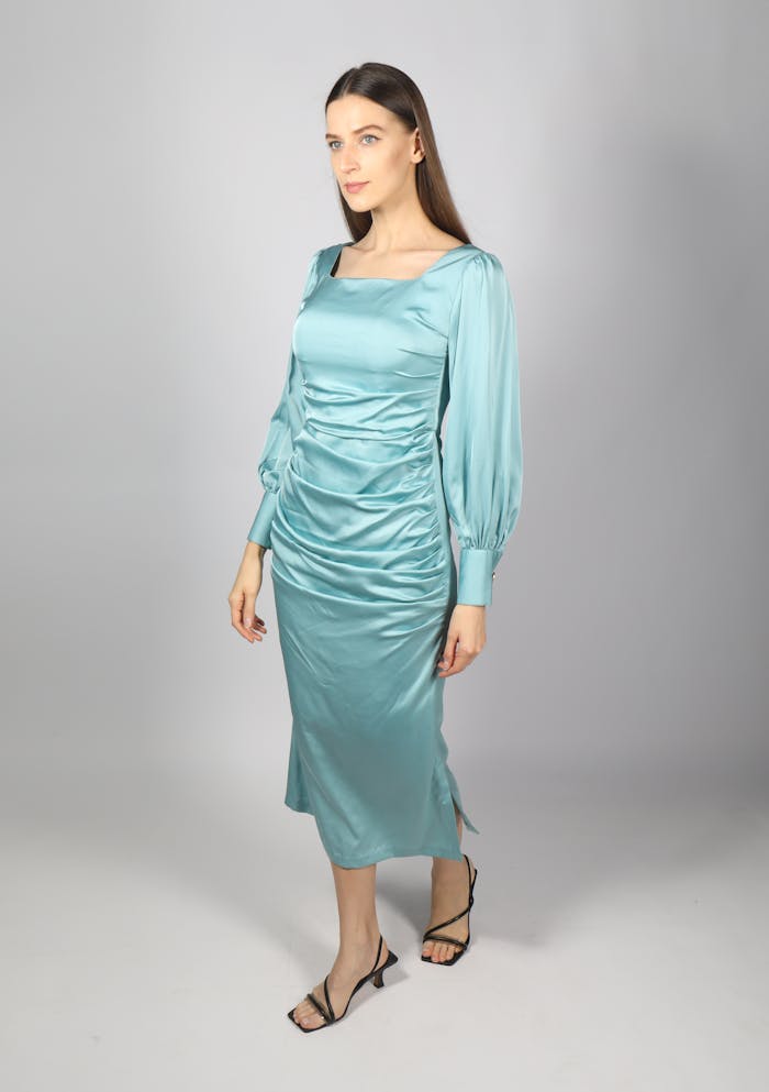 our-story A stylish woman in a blue satin dress posing confidently during a studio fashion photoshoot.