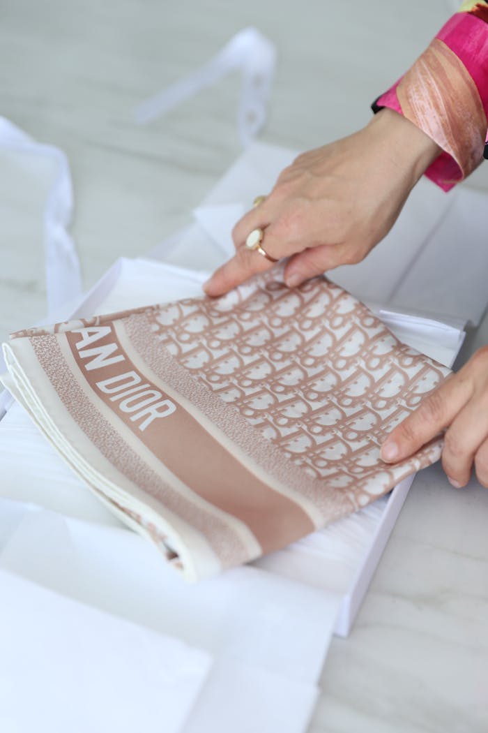 services-01 Hands gently folding a patterned luxury scarf, emphasizing delicate material and elegant design.