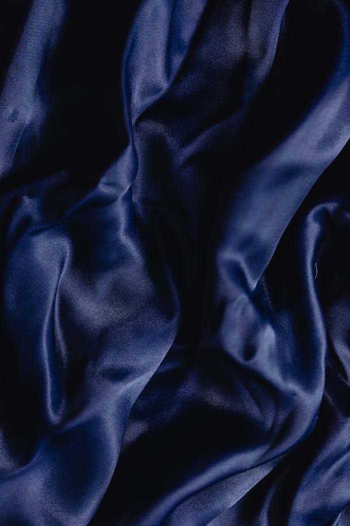 Close-up of dark blue silk fabric showcasing smooth texture and rich color, perfect for backgrounds.