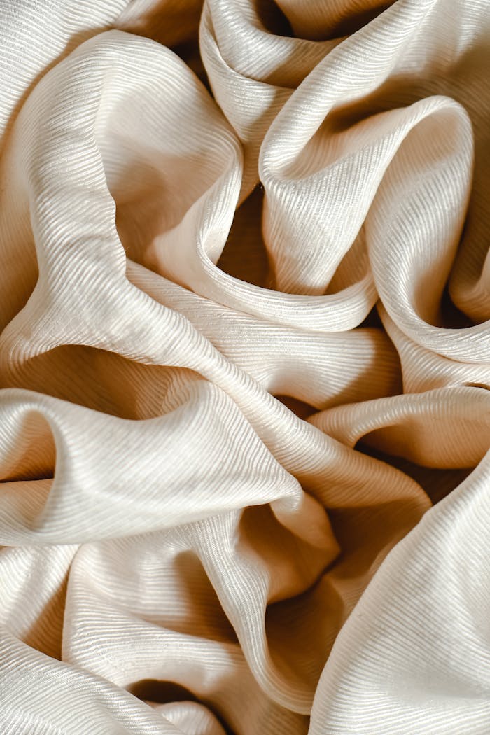 Close-up of luxurious cream fabric featuring intricate ruffles and textured design.
